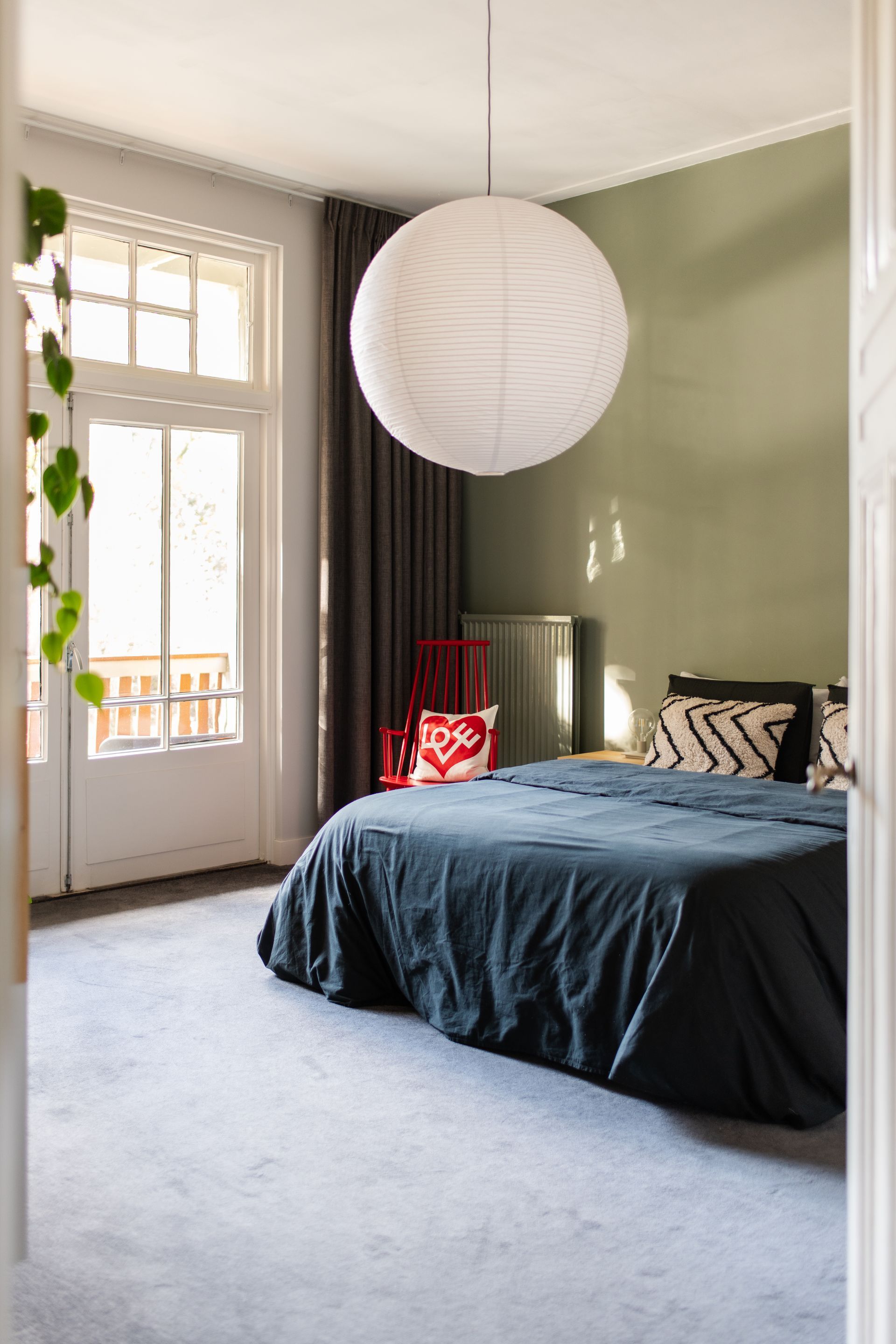 een slaapkamer met een groot bed en een papieren lantaarn die aan het plafond hangt.