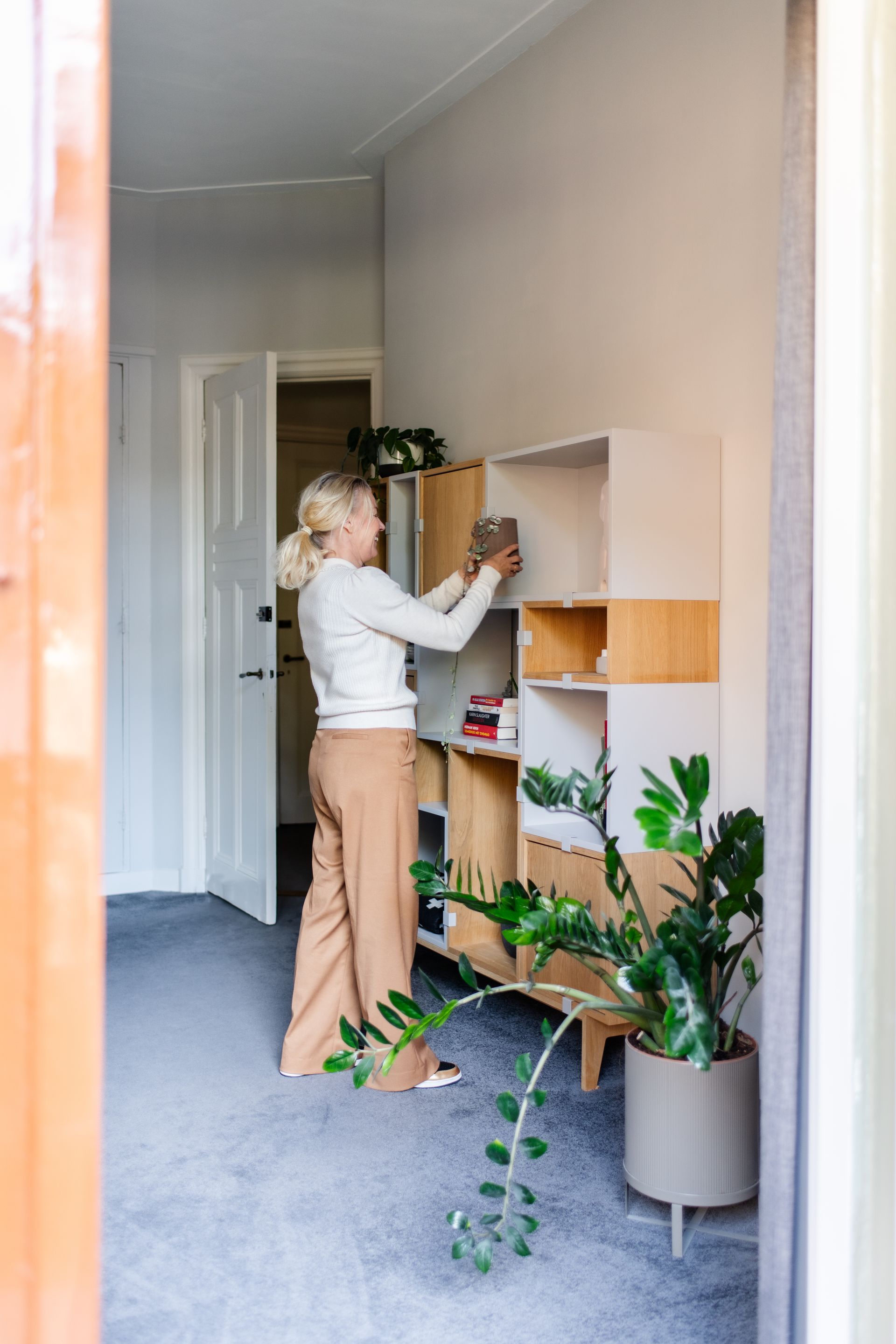 een vrouw staat naast een boekenplank in een kamer.