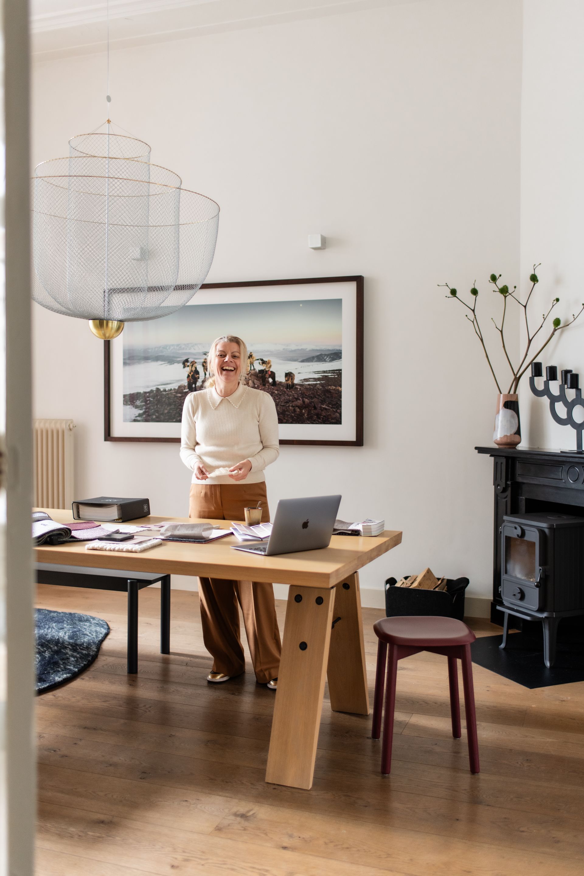 een vrouw staat aan een houten tafel met een laptop erop.