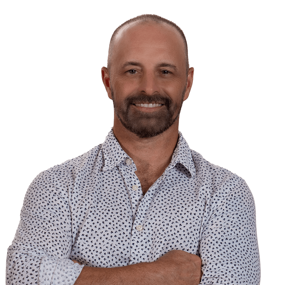 Smiling man with folded arms in a patterned button-up shirt against a white background