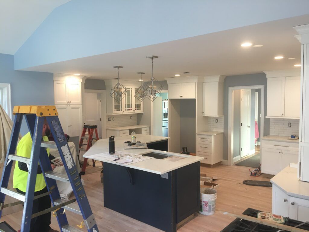 A man is standing on a ladder in a kitchen under construction.