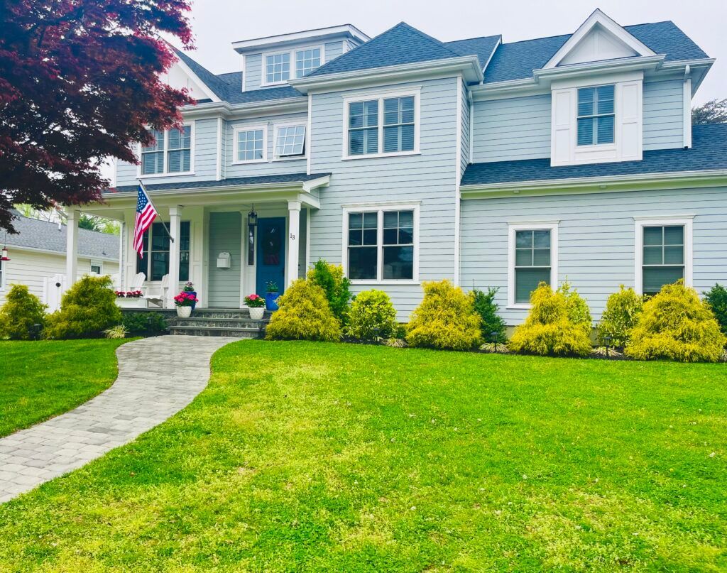 A large white house with a blue roof and a lush green lawn