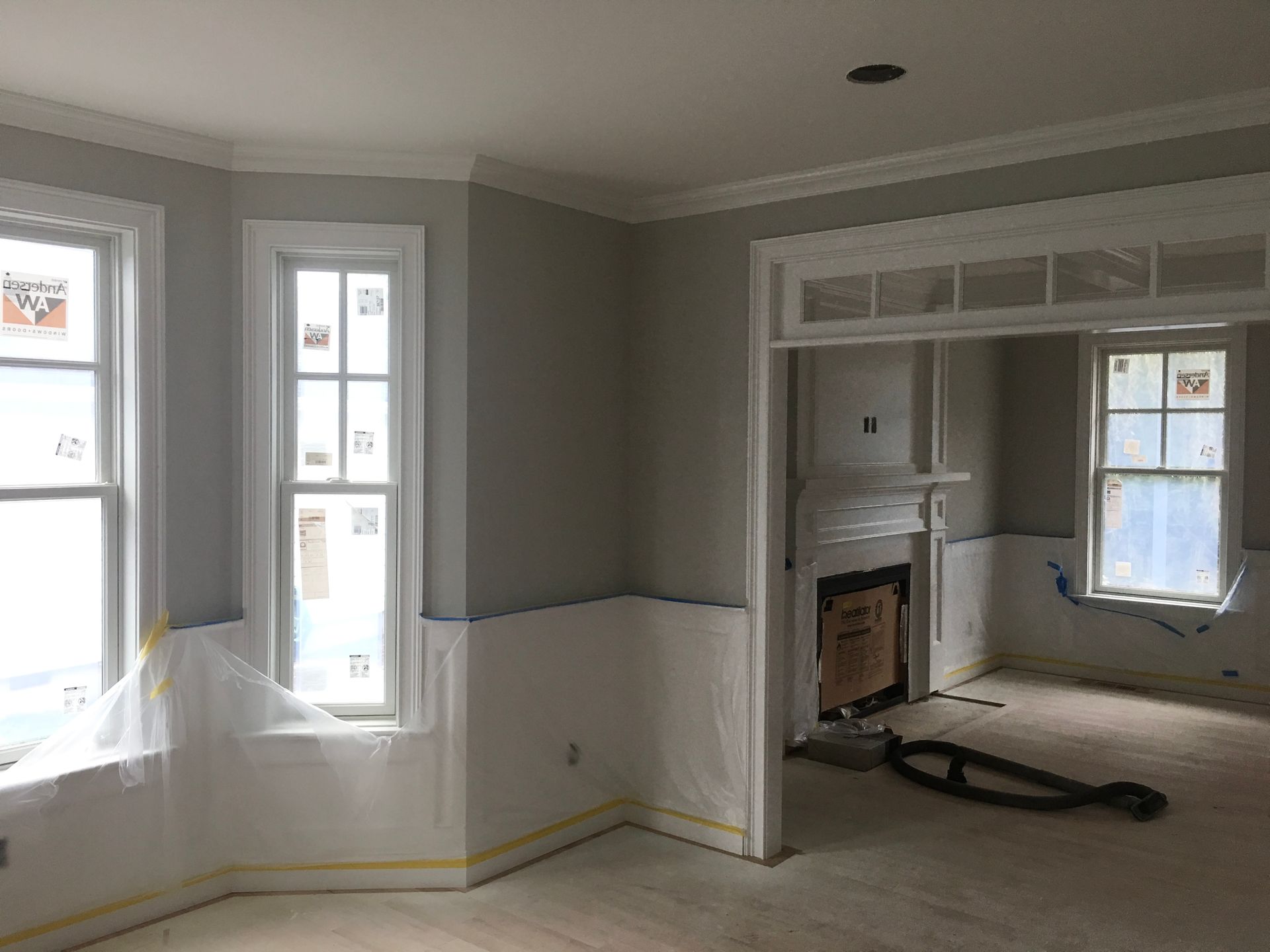 A living room with a fireplace and two windows under construction.