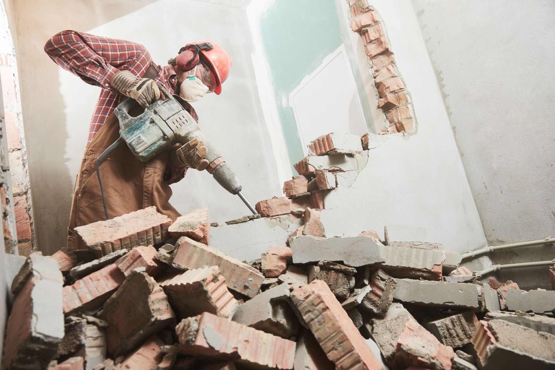 worker demolition hammer breaking interior wall