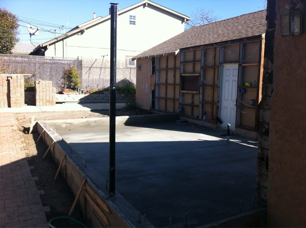 Backyard with a concrete patio, fence, and a small shed under construction