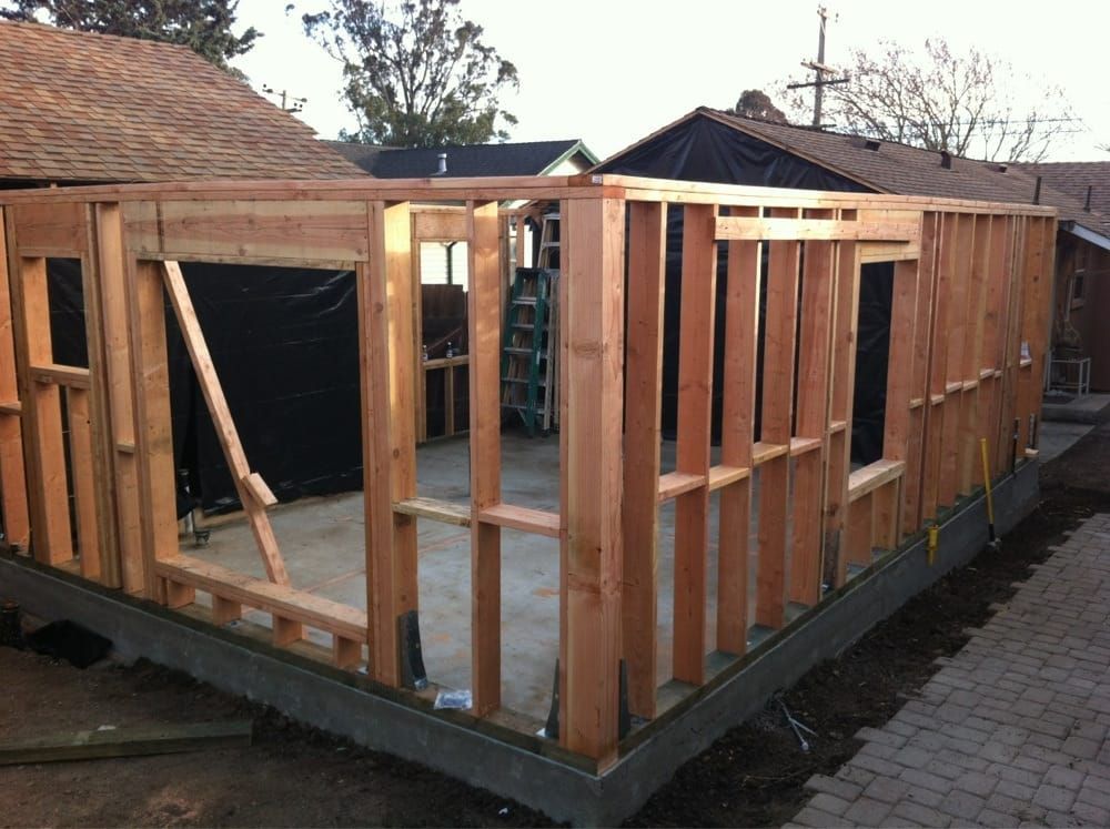Partially framed wooden house under construction on a concrete slab