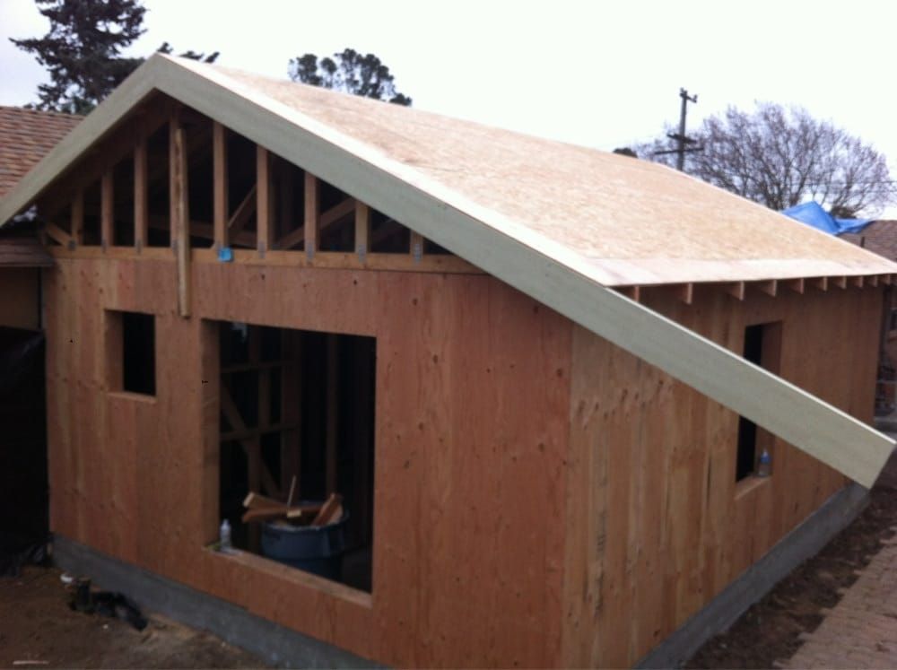 Partially built wooden house with open framing and a sloped roof under construction