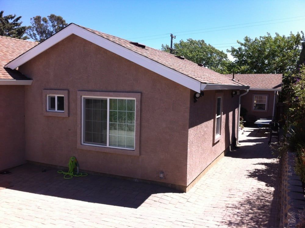 Exterior of a stucco house with a brick driveway and shaded side yard
