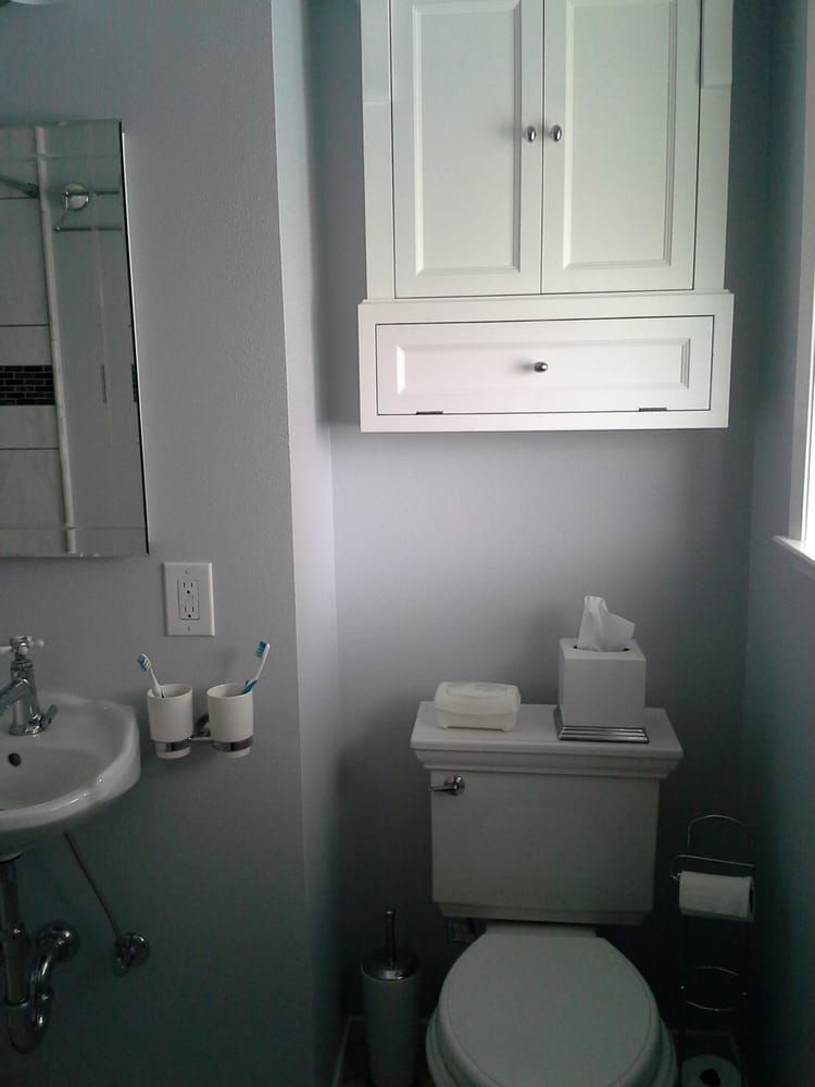 Small bathroom with toilet, sink, mirror cabinet, and wall-mounted storage cabinet.