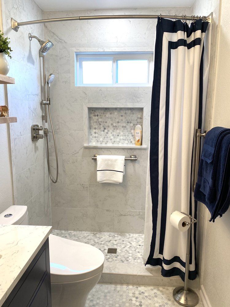 Modern bathroom with tiled shower, black-and-white curtain, wall niche, and toilet in the foreground
