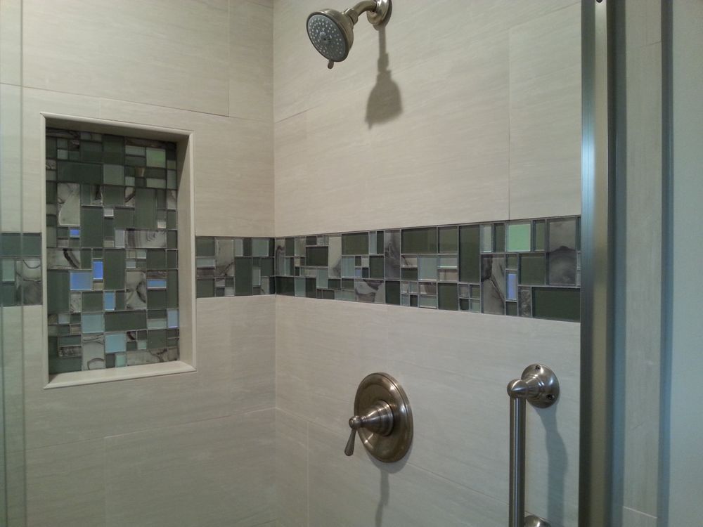 Modern tiled shower with mosaic accent strip, built-in niche, and chrome shower fixtures