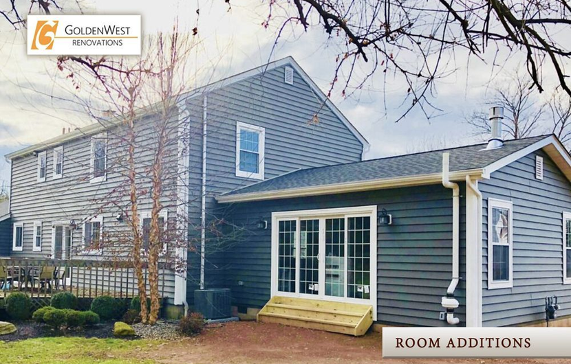 Gray house exterior with blue siding, bay window room addition, and bare winter trees