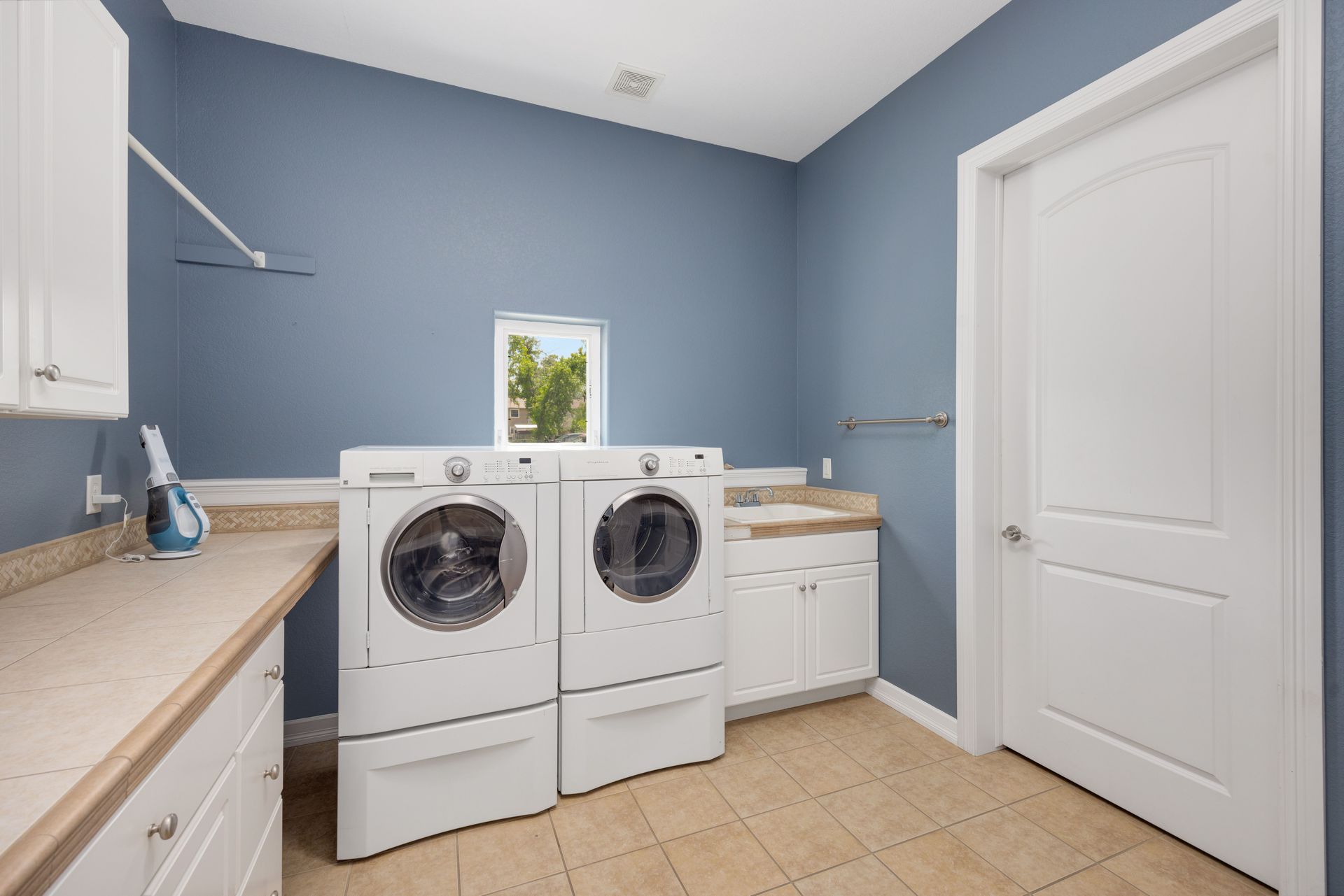 Laundry room with washer and dryer, blue walls, white cabinets, and a closed door