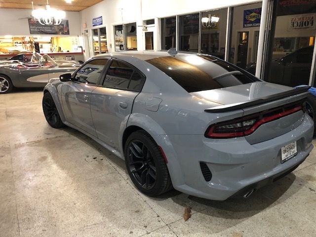 Gray Dodge Charger in a garage with a classic car.