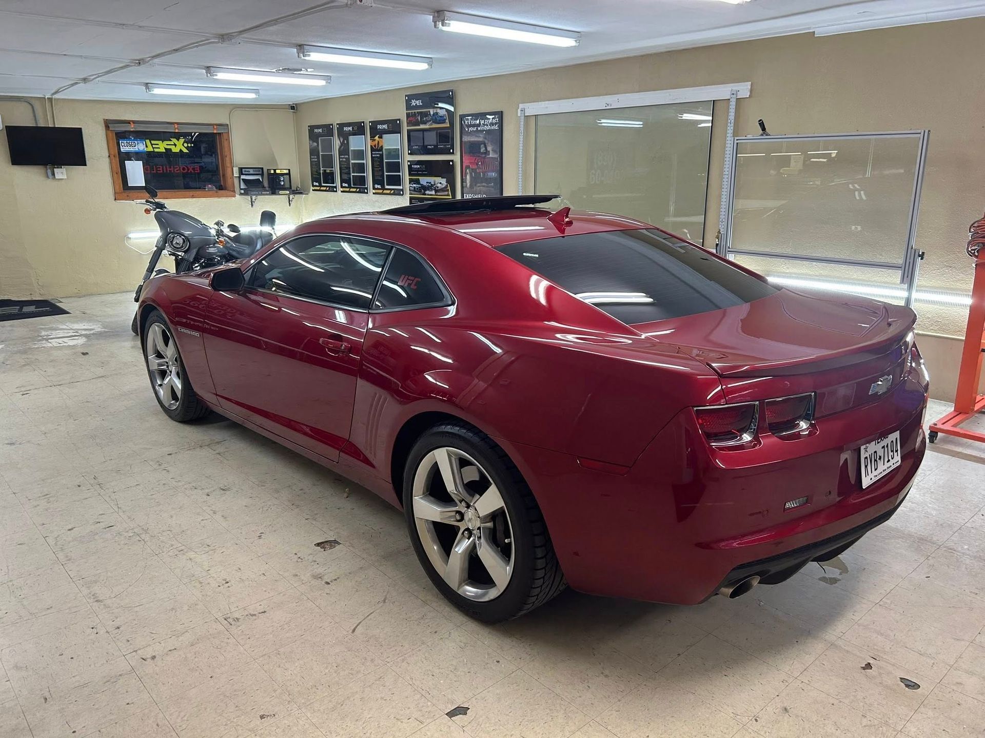 Red Camaro in a garage, trunk open.