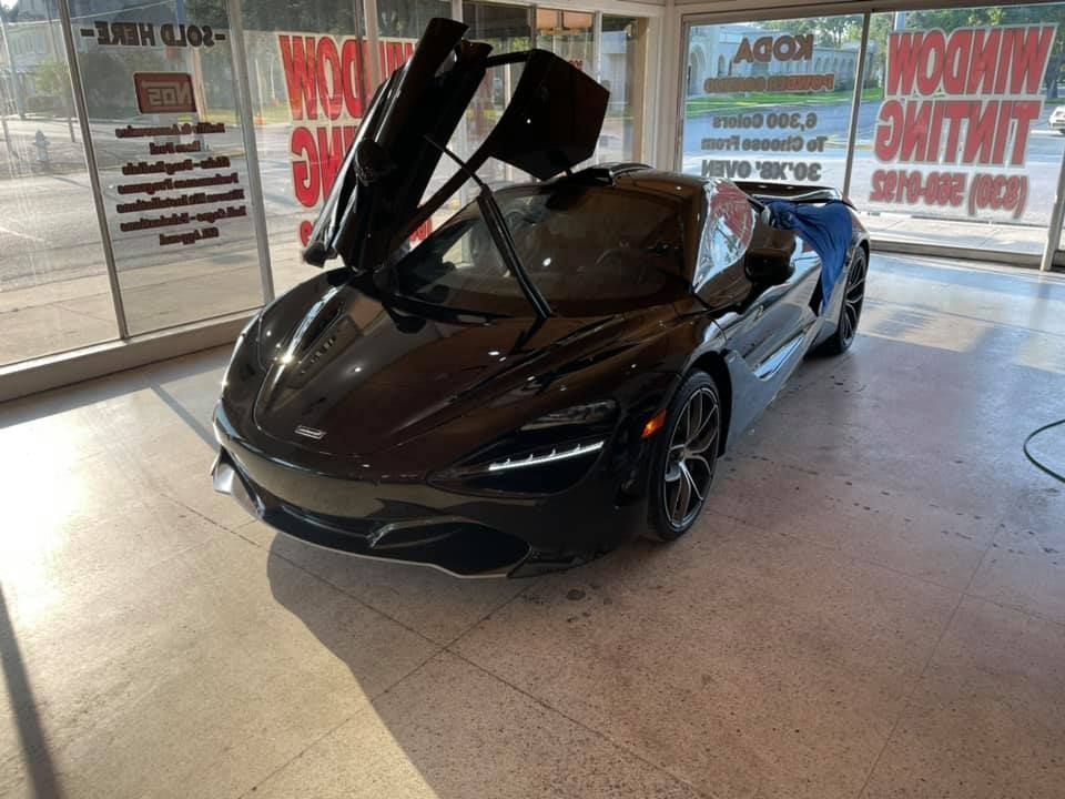 Black McLaren sports car with doors open in a shop.