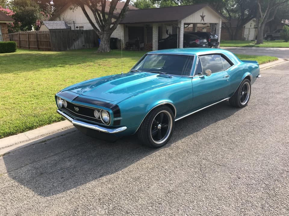 Teal classic Camaro parked on a suburban street.