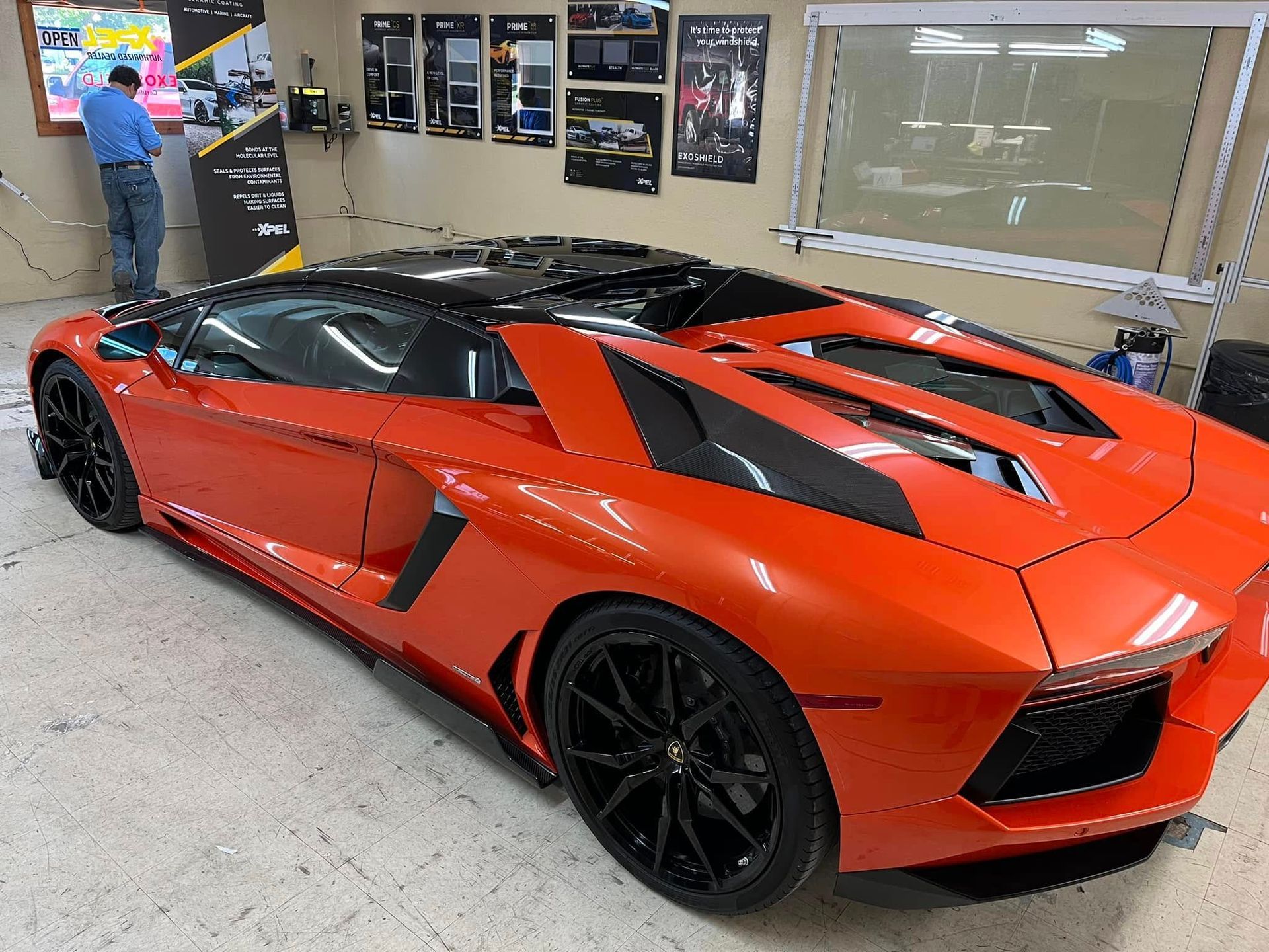 Orange Lamborghini sports car with black roof and wheels parked in a shop.