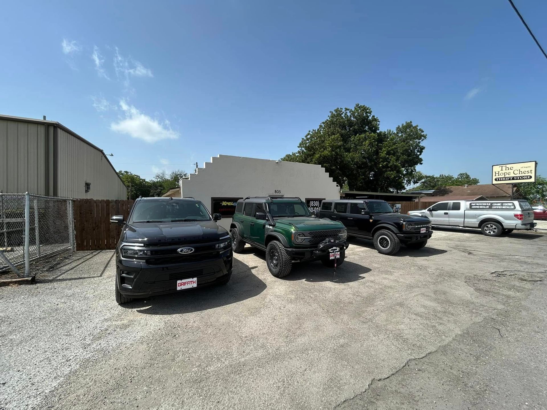 Several vehicles parked outside a building under a clear blue sky.