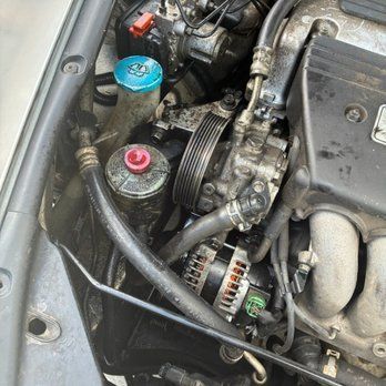 Mobile mechanic changing a car battery with a service truck nearby.
