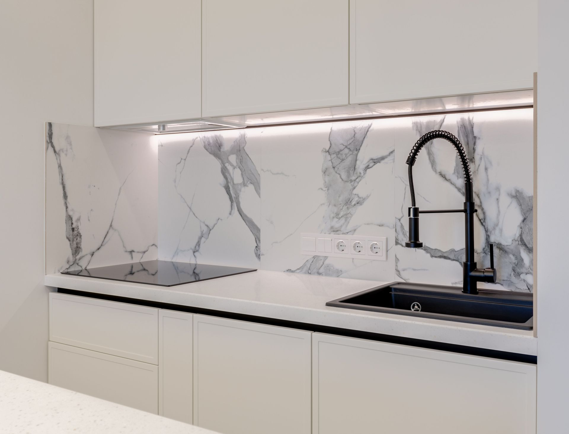A kitchen countertop with sink and marble backsplash