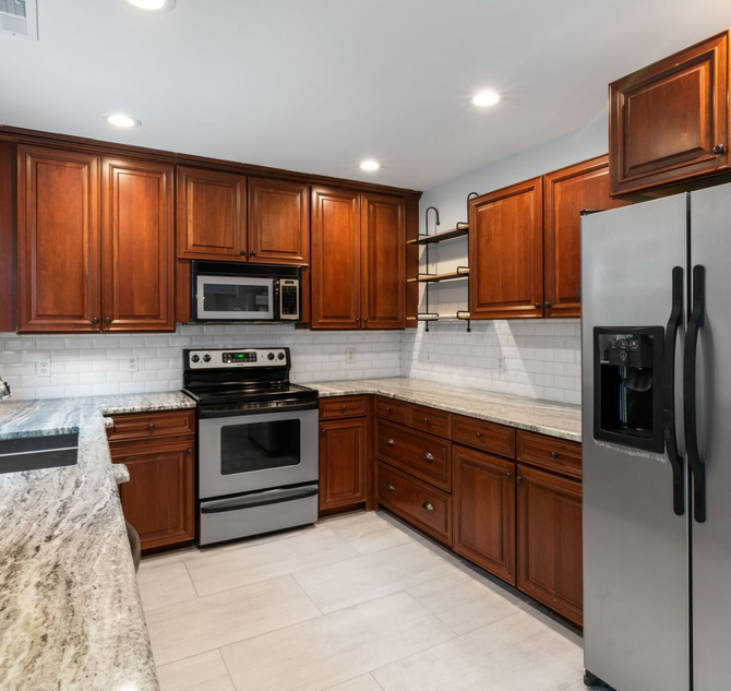 A modern kitchen with marble countertops and mohongany wood cabinets.