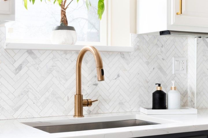 A kitchen sink with a tile backsplash