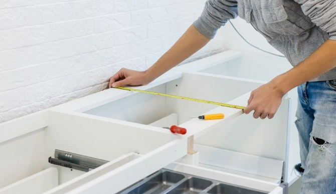 Crew member measuring for drawer installation