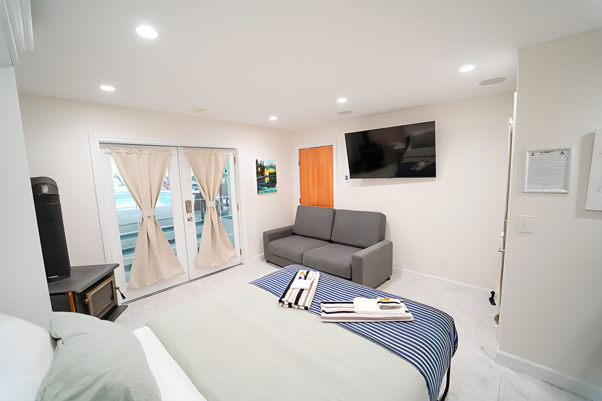 Bedroom with a bed, couch, TV, and glass doors leading to an outdoor space.