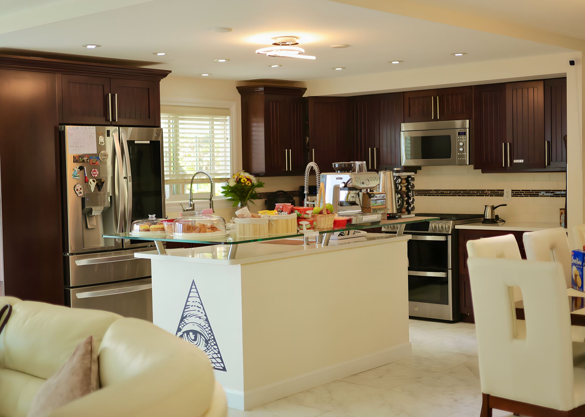 Kitchen with dark wood cabinets, stainless steel appliances, island, and white seating.