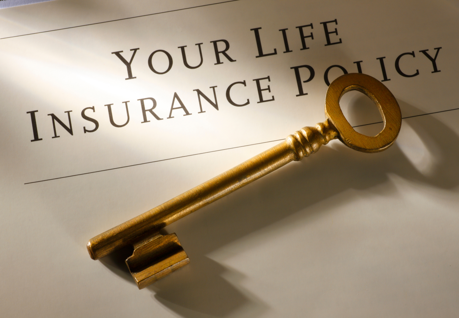 A gold key sits on top of a life insurance policy
