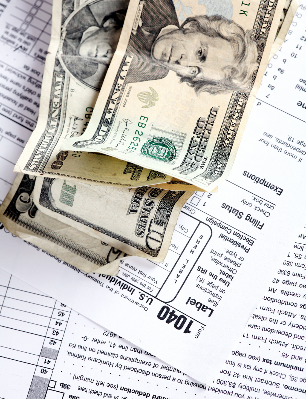 A stack of 20 dollar bills on top of 1040 tax forms