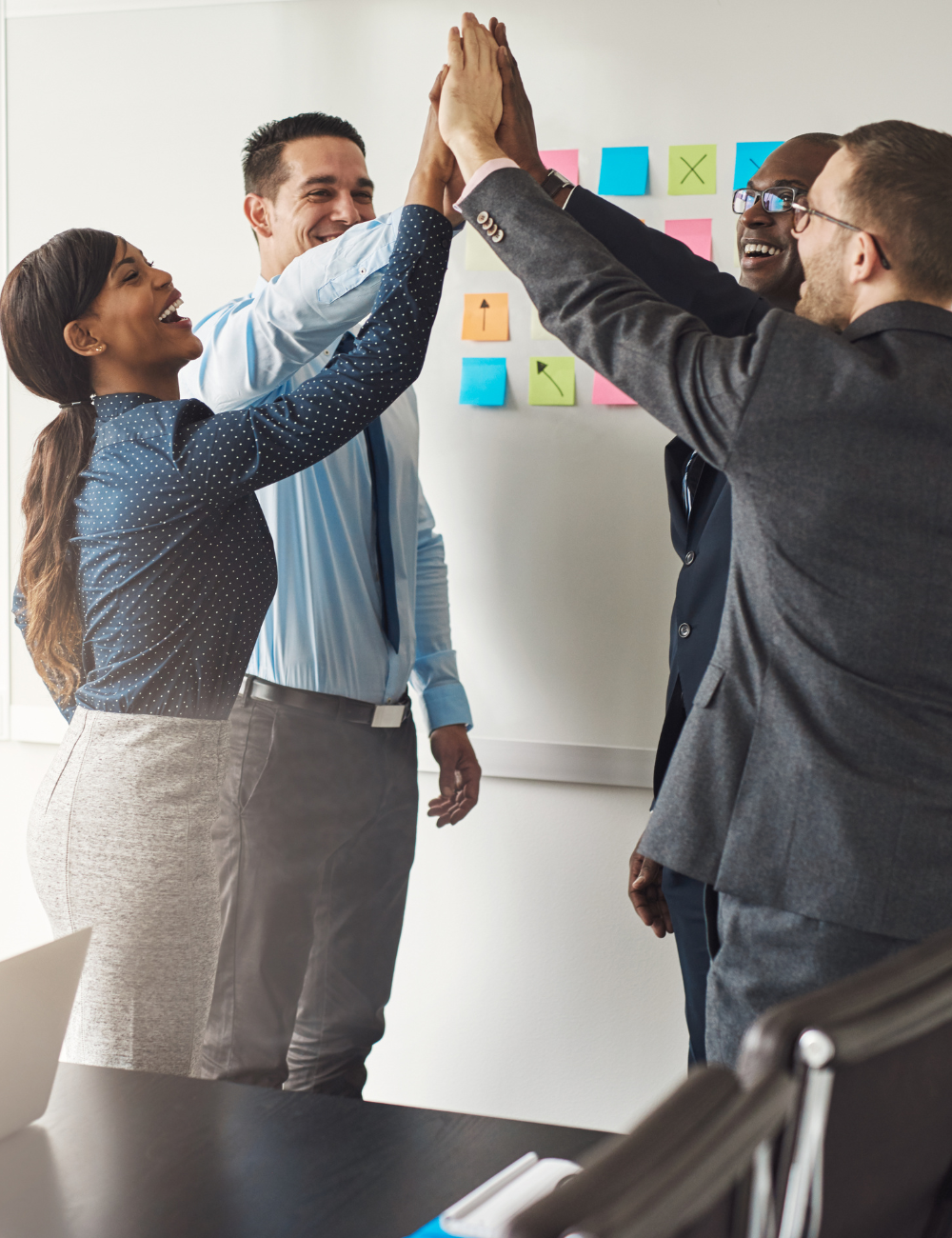 A group of people are giving each other a high five in an office.