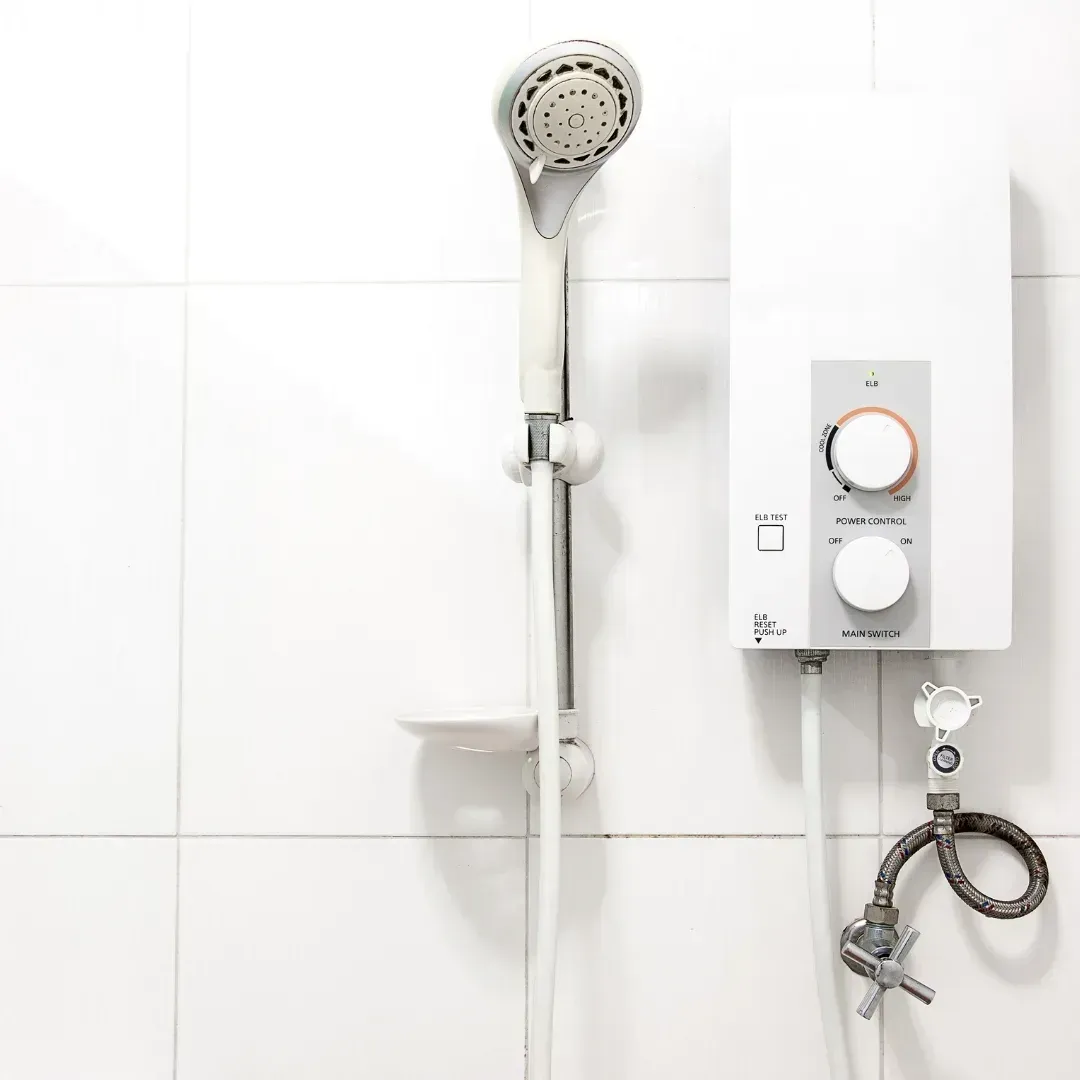 White bathroom shower with handheld head and wall-mounted water heater controls.