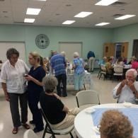 Community room with people seated at tables and mingling during a social gathering