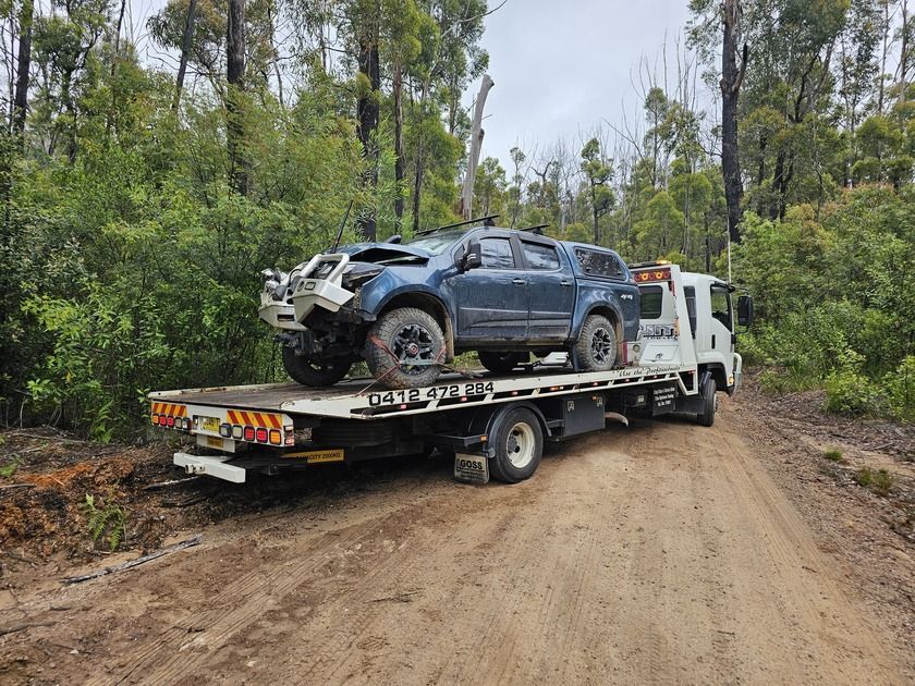 A Car is Being Towed by a Tow Truck on a Dirt Road — Optimum Towing in Bomaderry, NSW