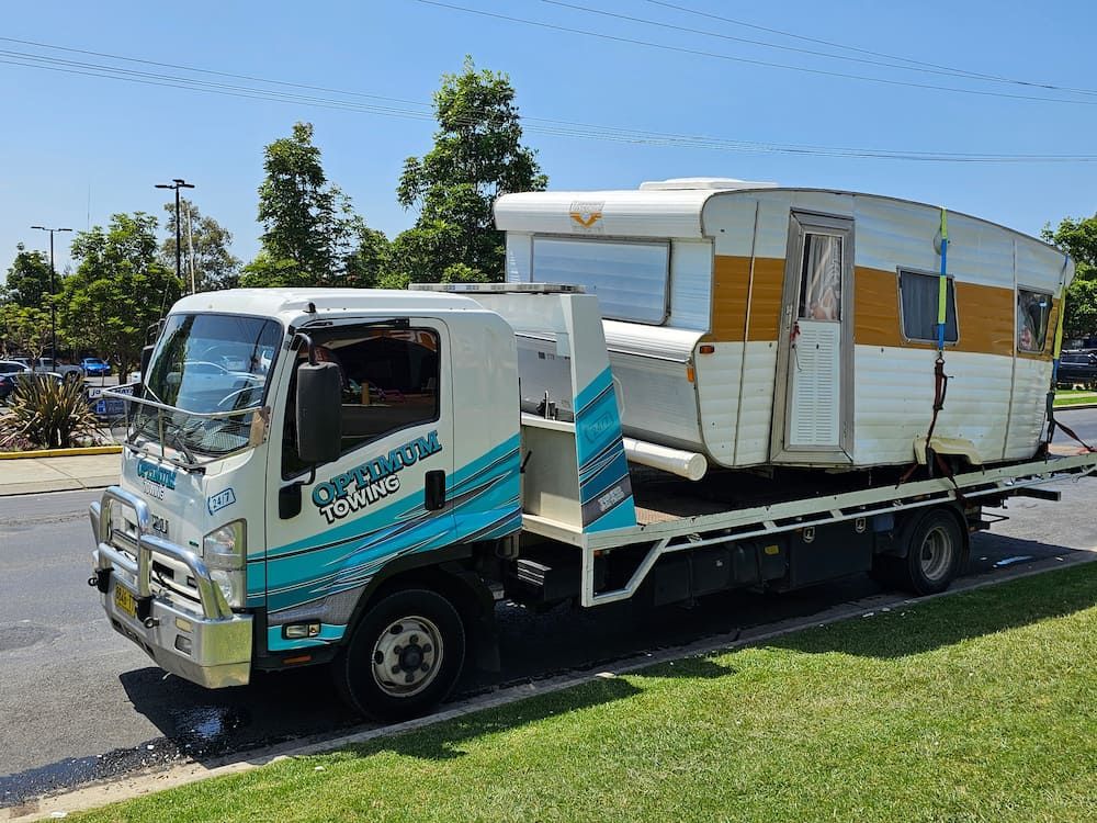 A Tow Truck is Carrying a Camper on the Back of It — Optimum Towing in Sanctuary Point, NSW
