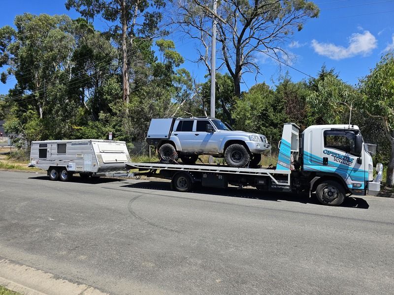 A Tow Truck is Carrying a Truck and a Trailer Down the Road — Optimum Towing in Bomaderry, NSW