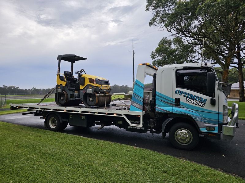 A Tow Truck is Carrying a Yellow Roller on the Back of It — Optimum Towing in Bomaderry, NSW
