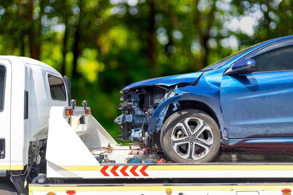 A Blue Car is Being Towed by a Tow Truck — Optimum Towing in Culburra Beach, NSW