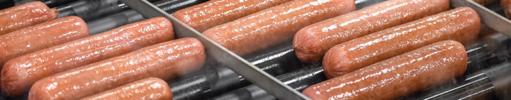 Sausages grilling on metal racks over a barbecue, browning with grill marks.