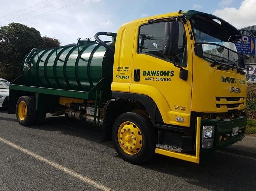 A yellow and green truck from rawson 's is parked on the side of the road.