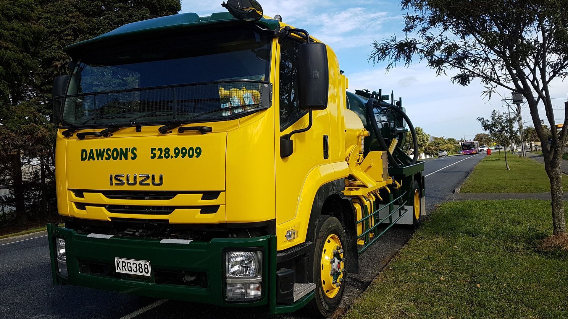 A yellow and green truck is parked on the side of the road.