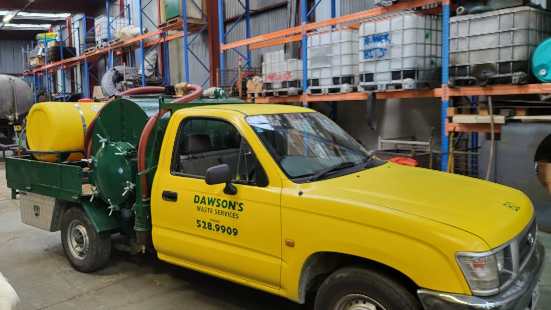 A yellow and green truck is parked in a warehouse.