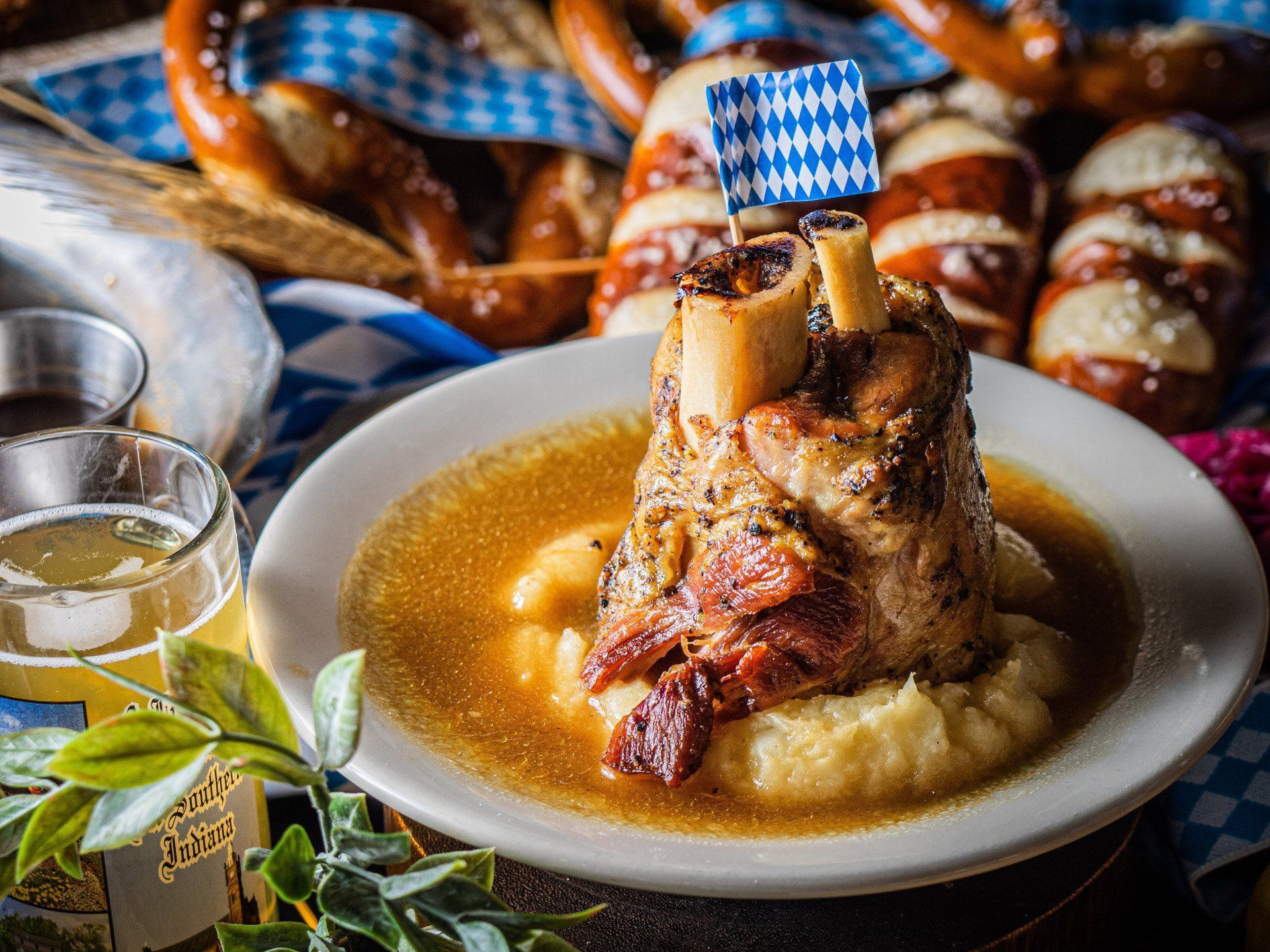 German-style pork knuckle on mashed potatoes with gravy, served with pretzels and a beer in a festive setting
