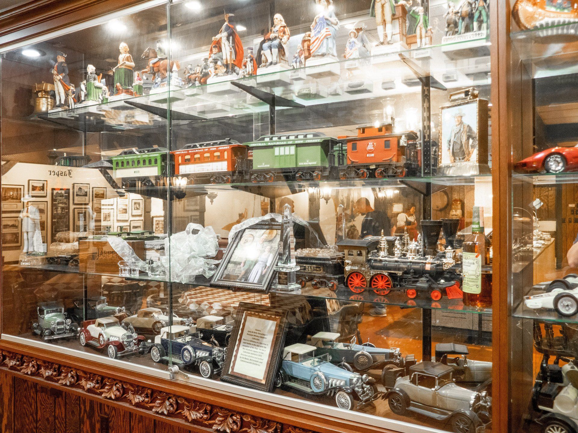 Glass display case filled with miniature cars, trains, and figurines in a shop window