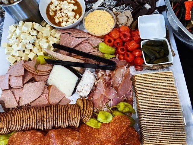 Assorted charcuterie board with meats, cheeses, grapes, pickles, and crackers on a tray