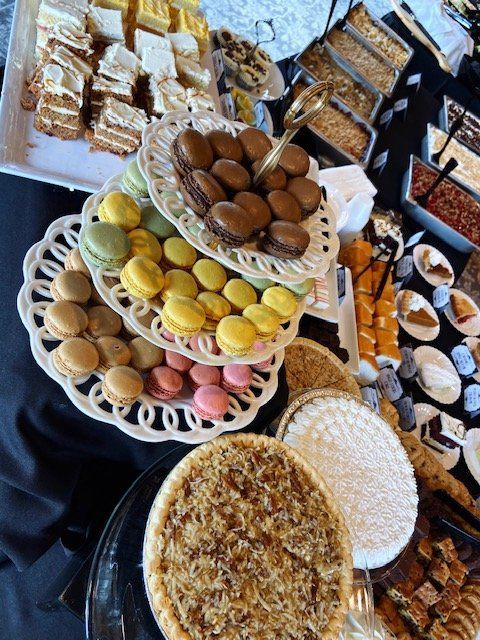 Assorted Arabic sweets and pastries on tiered trays, including cookies, baklava, and confections in a dessert display