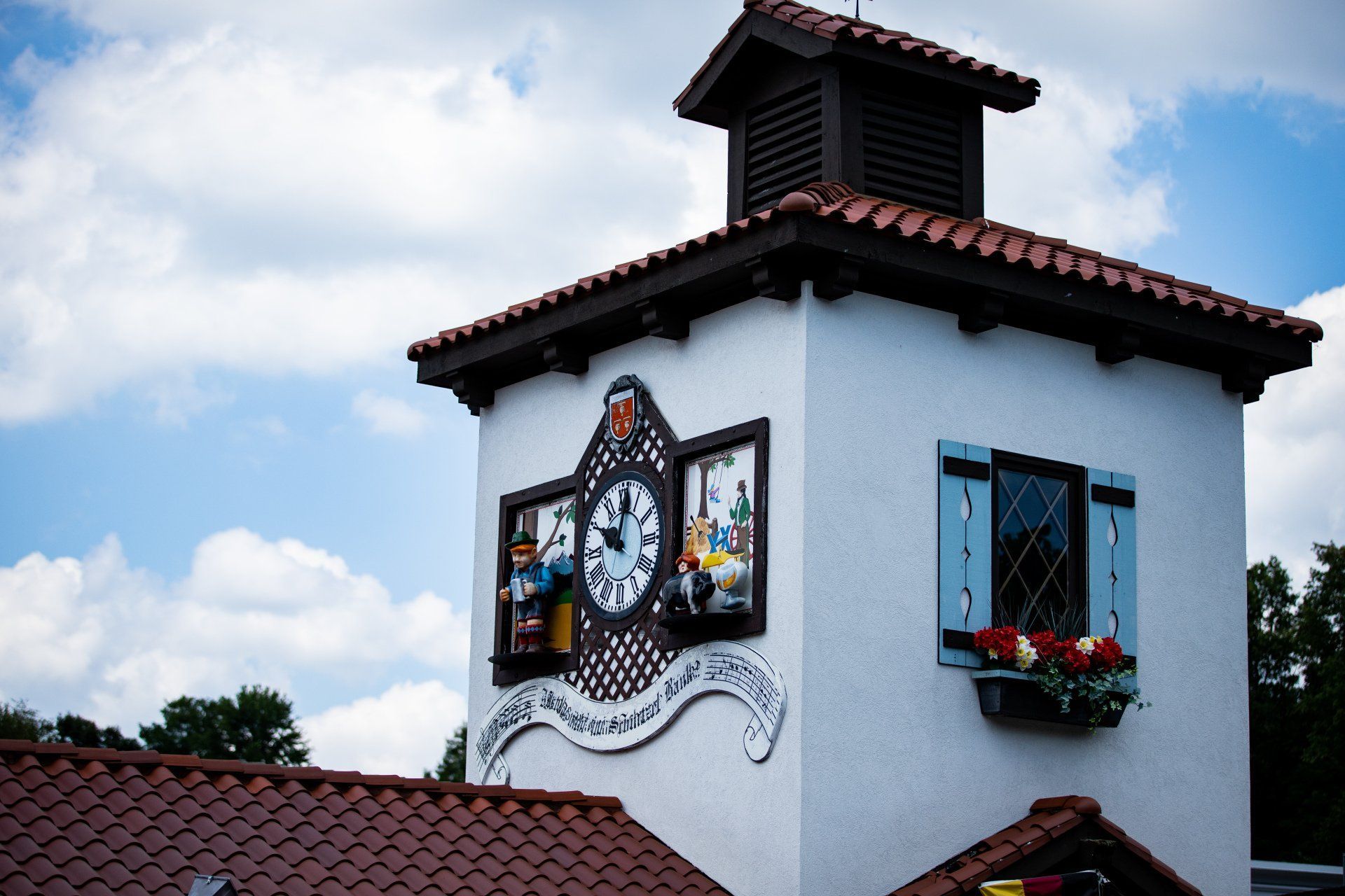 Clock tower with colorful clock faces on a white building under a cloudy sky