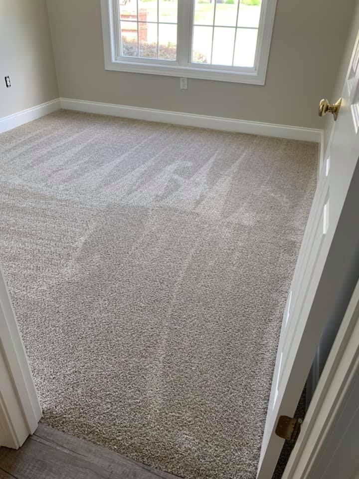 A bedroom with a large carpeted floor and a window.